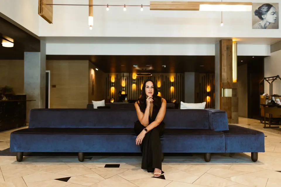 Kristin Darga, executive coach, seated on a blue sofa in a hotel lobby